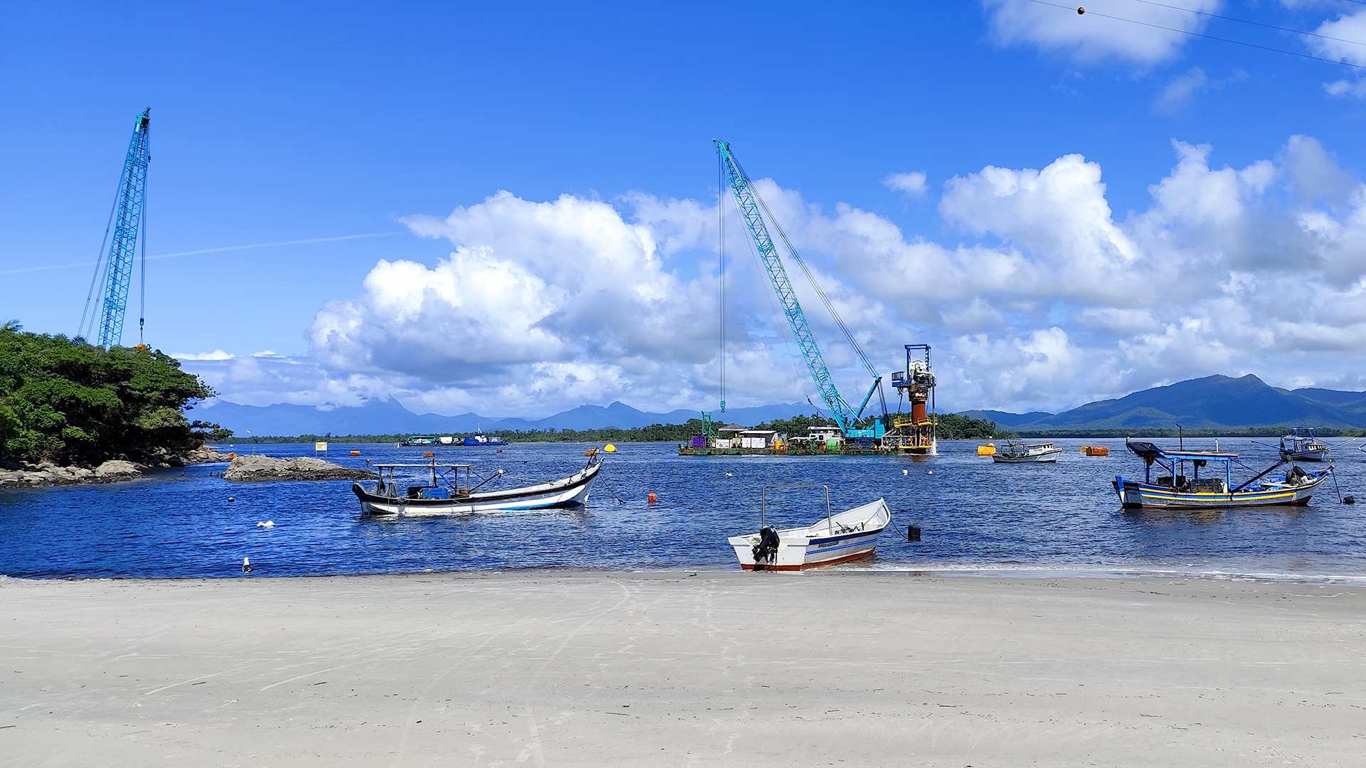 obras das ponte de guaratuba, barcos de pesca na praia de caieiras, baía de guaratuba com céu azul com nuvens, mar calmo e azul,