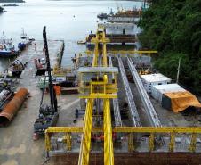 Vista aérea do canteiro de obras da ponte de guaratuba com guindastes, barcaças e estruturas de concreto em construção 