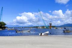 obras das ponte de guaratuba, barcos de pesca na praia de caieiras, baía de guaratuba com céu azul com nuvens, mar calmo e azul, 